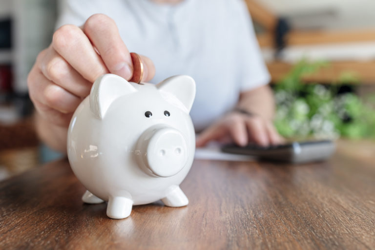 Piggy bank savings man putting a coin into a pink piggybank