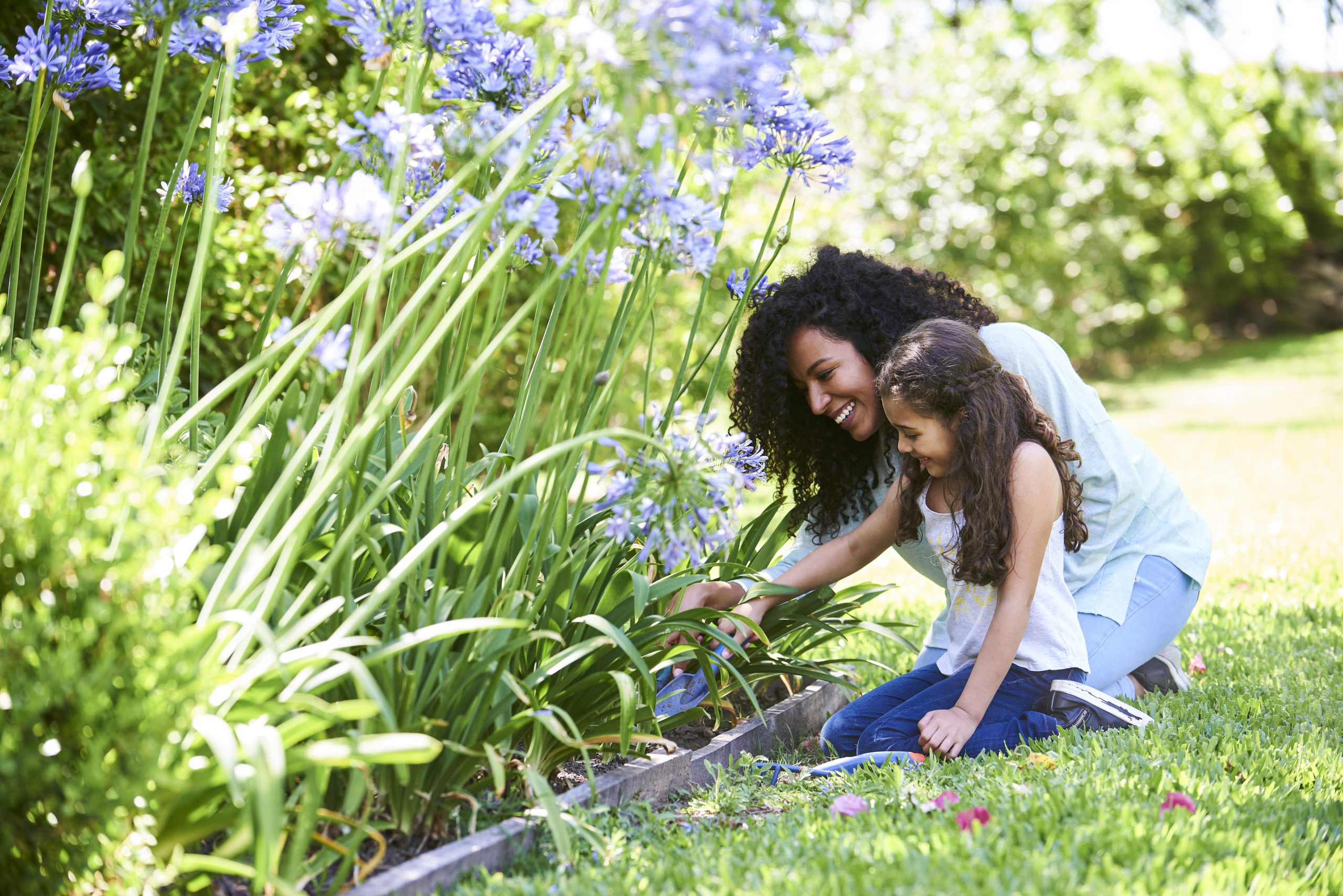 Mother and daughter planting flowers in garden