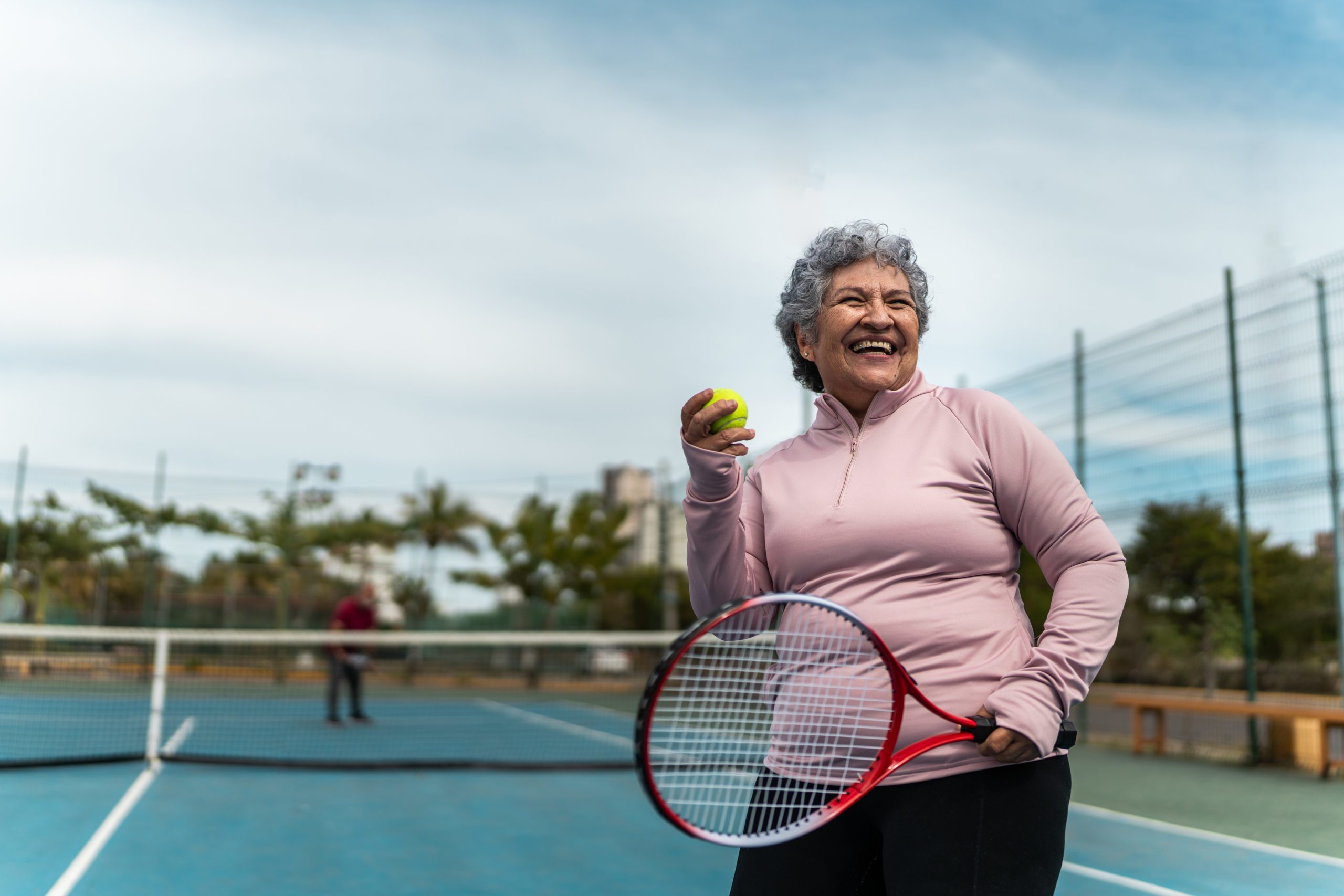 Senior woman playing tennis at sports court