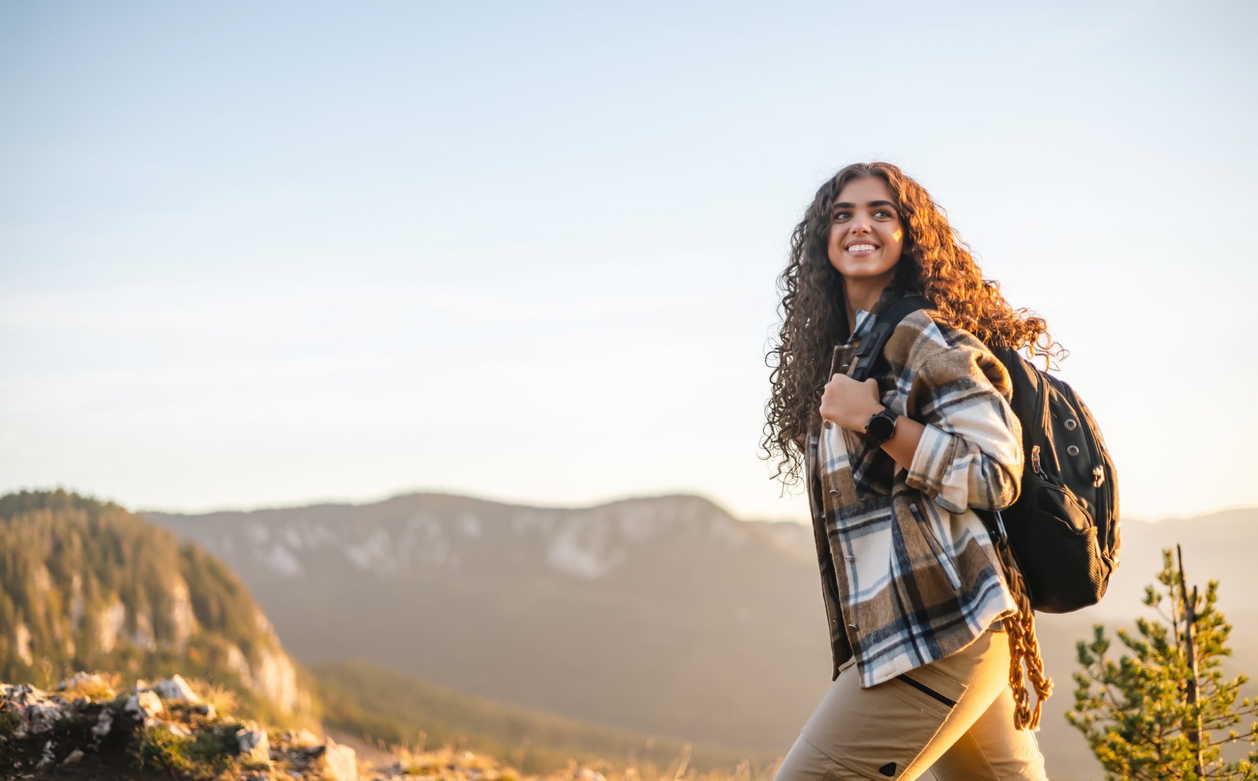 Woman hiking with backpack on mountain trail at dawn