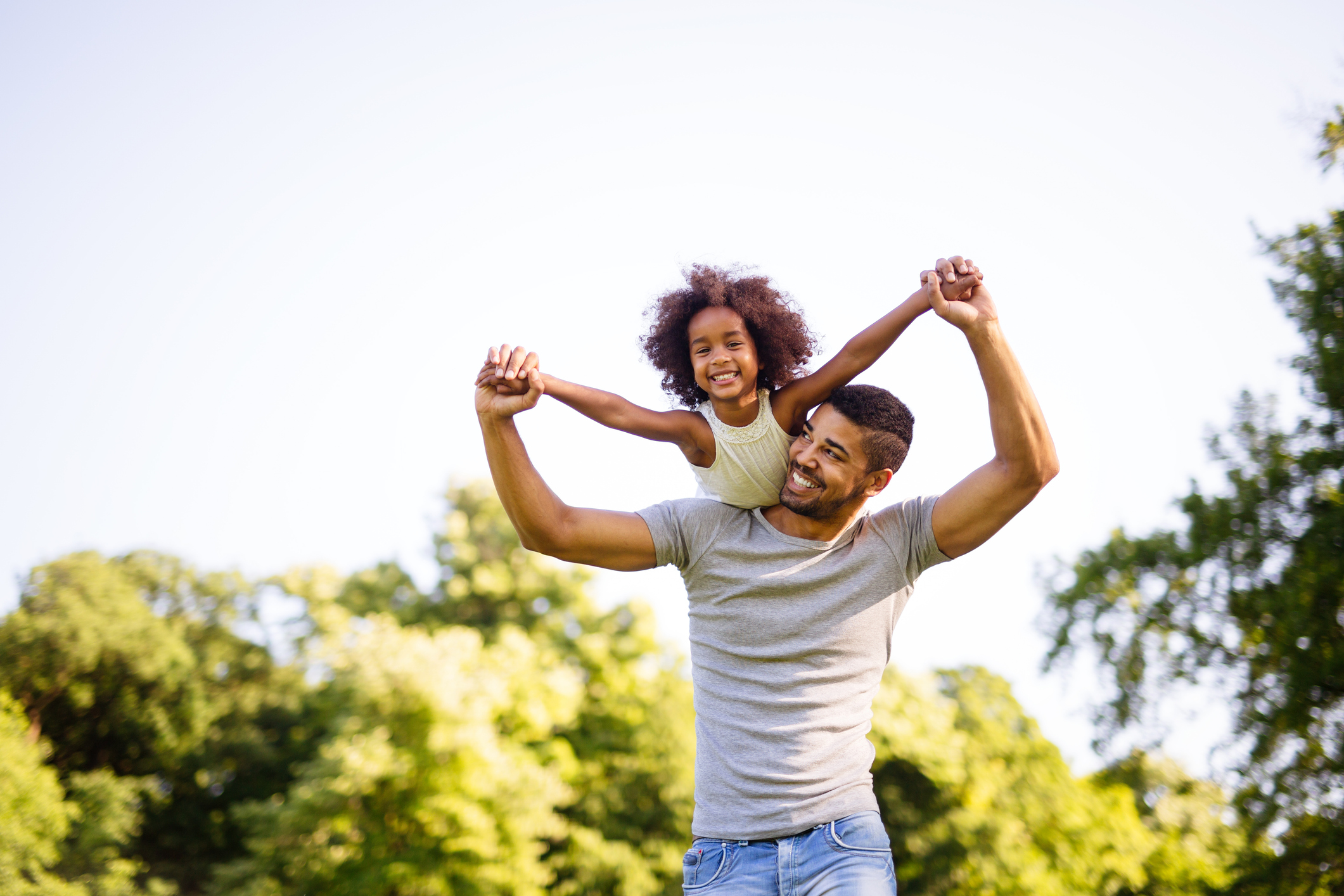 Portrait of happy black father carrying daughter on back outdoors Family happiness love concept
