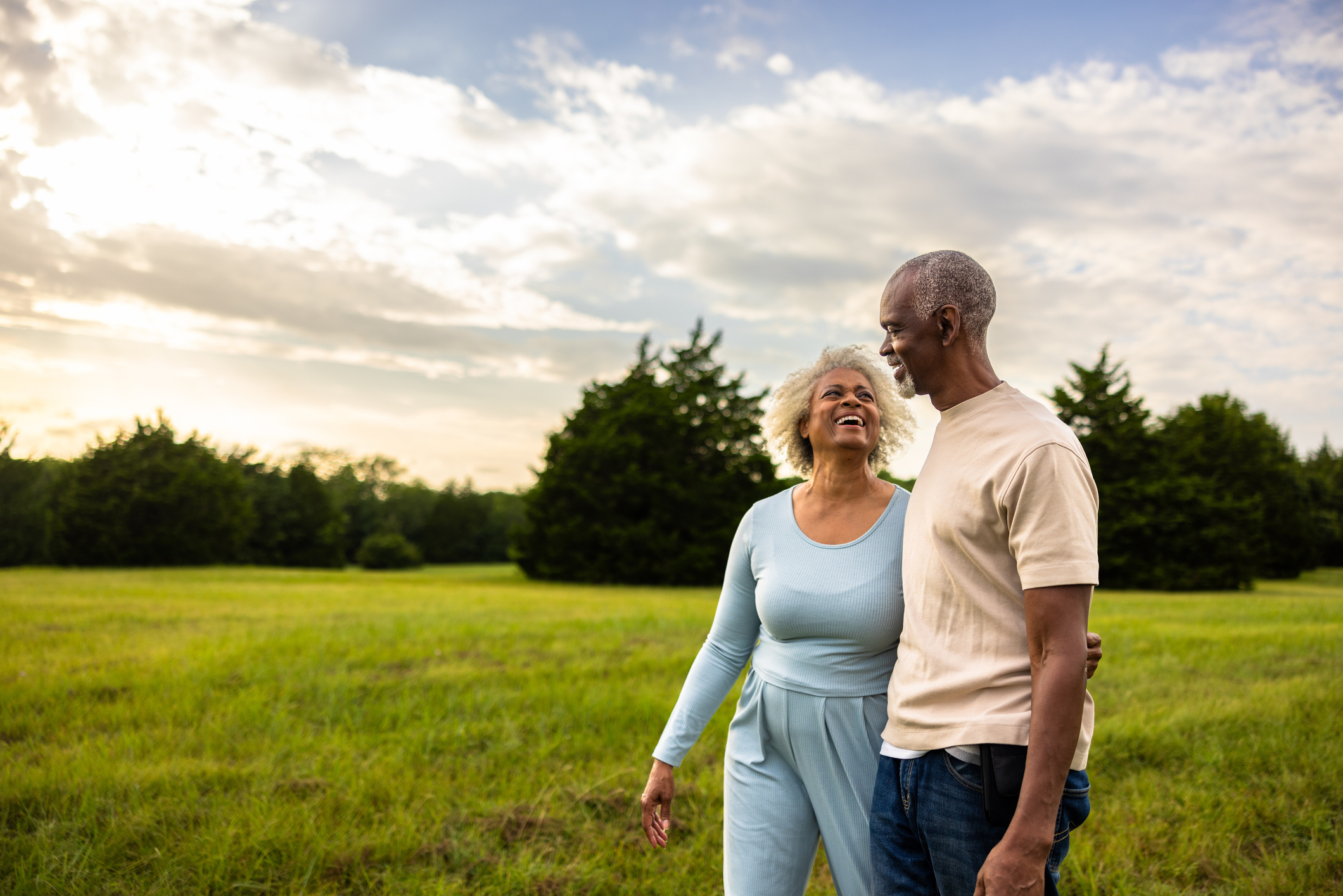 Senior black couple walking outdoors at sunset in the pasture