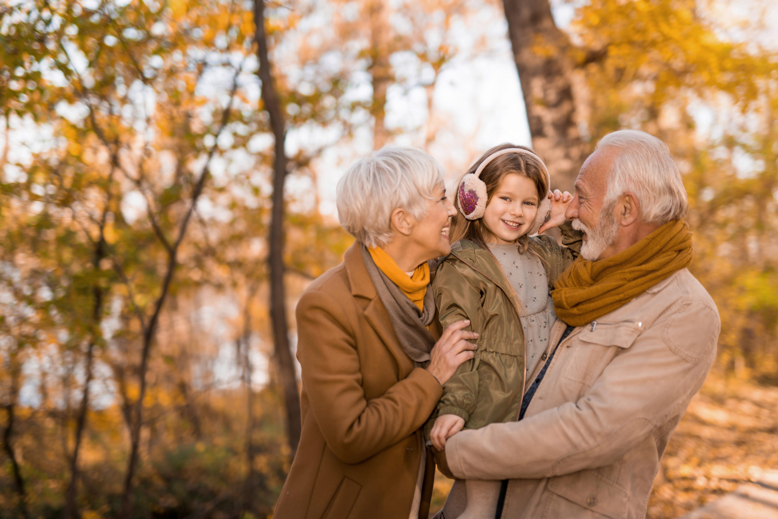 Happy seniors playing and talking with their little granddaughter in the park