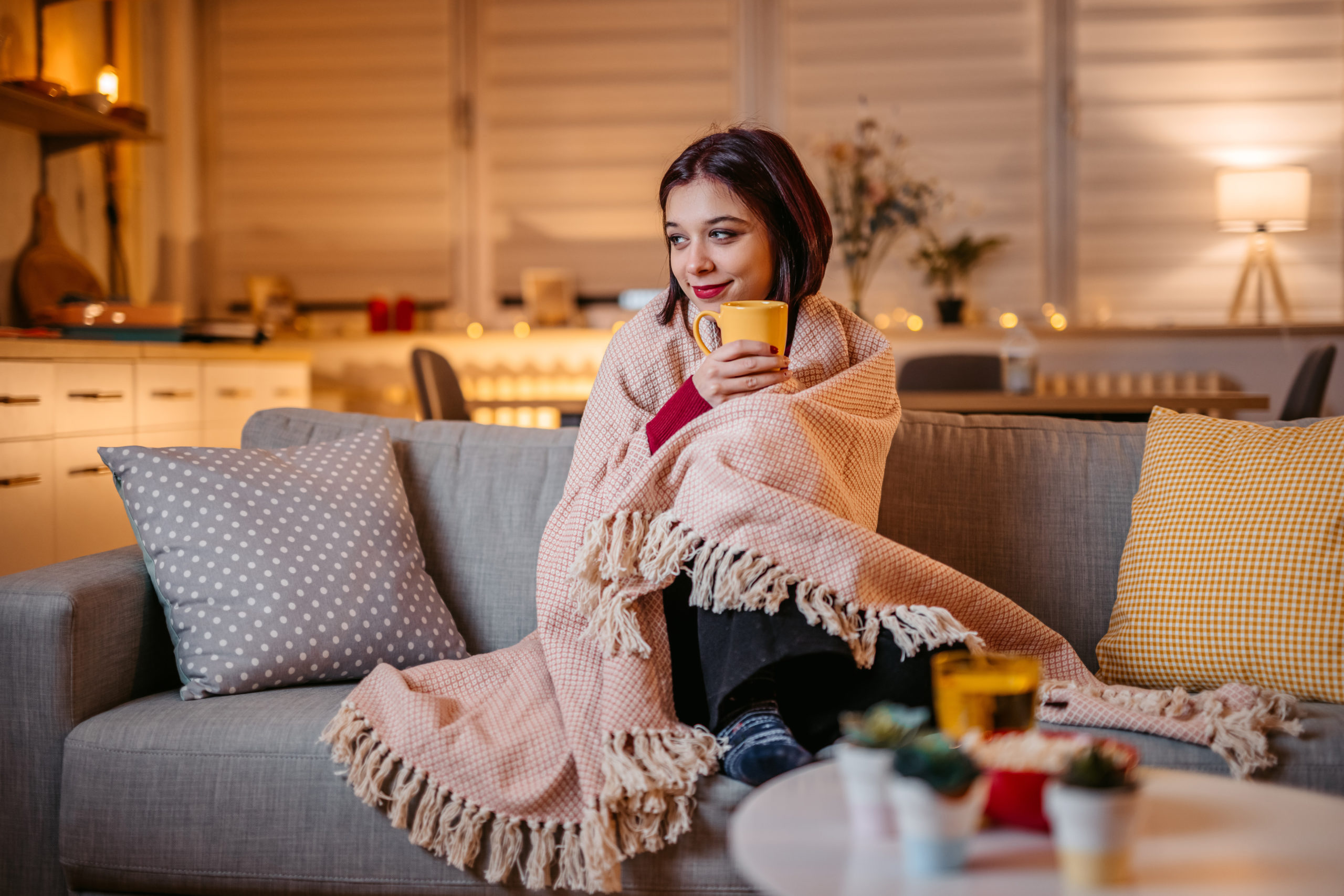 Beautiful woman drinking hot tea wrapped in blanket
