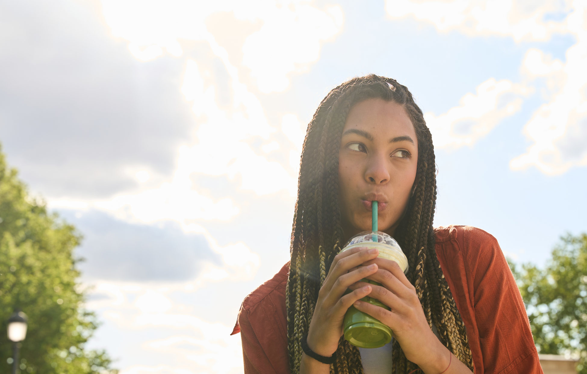 Young latina woman enjoying a refreshing drink outdoors in summer